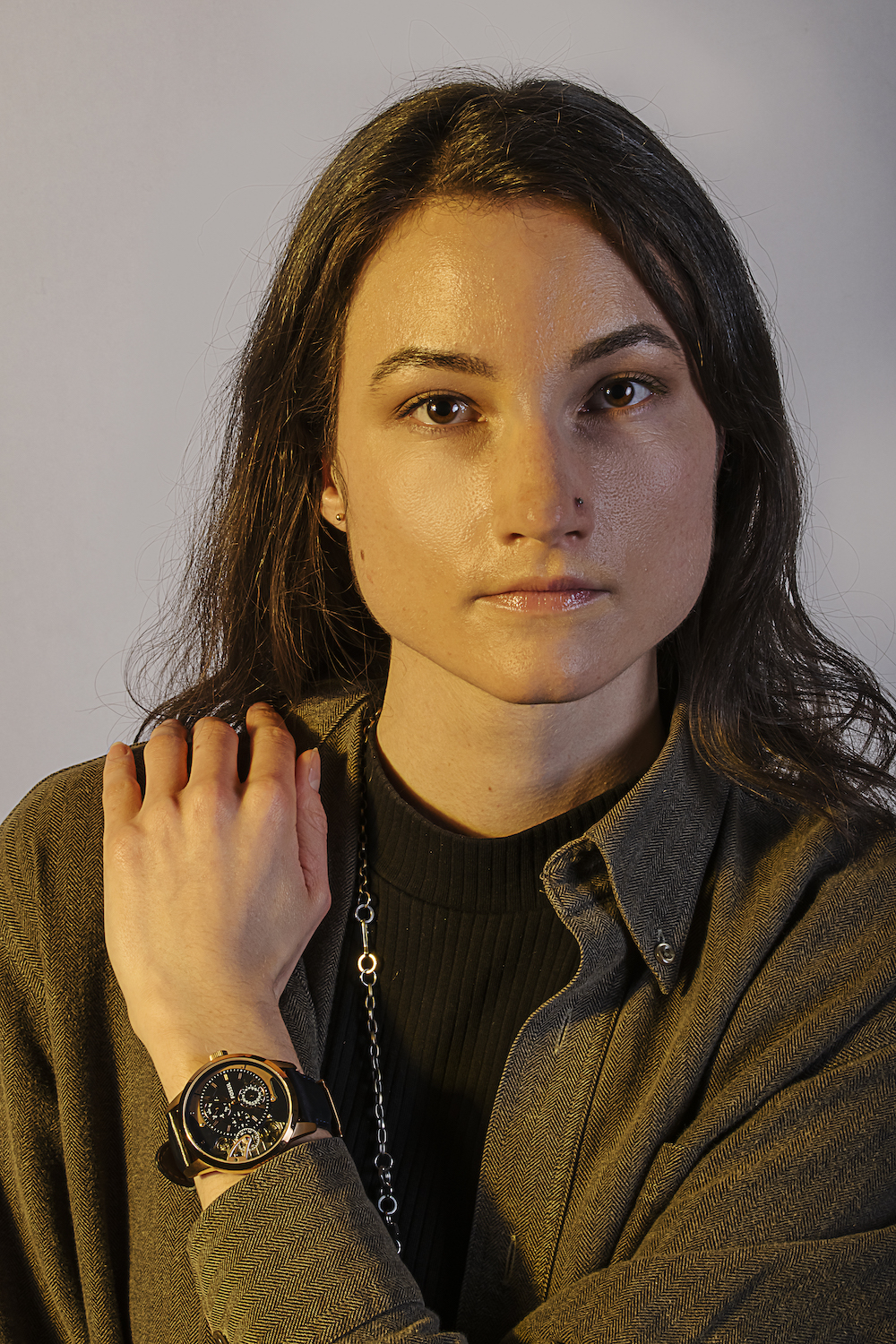 Studio portrait of young woman wearing fossil watch.